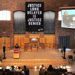 Banner hangs in Hoversten Chapel reading "Justice long delayed is justice denied."